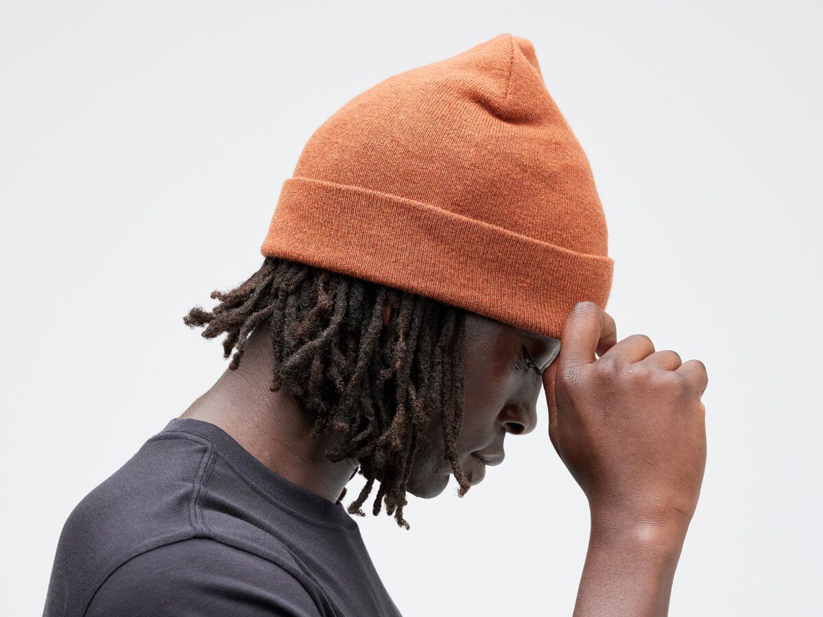 Man looking down wearing orange Stance beanie